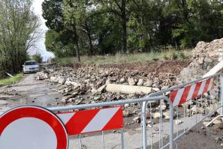 Detriti del muro crollato lungo la strada e cartello di divieto di accesso