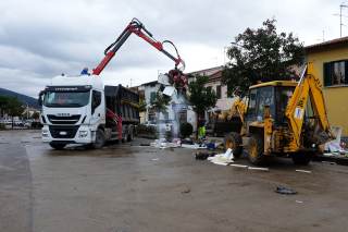 Trattore e camion con ragno esterno mentre raccolgono i rifiuti alluvionati in strada