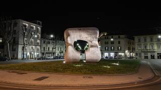 Ripresa serale del monumento Forma squadrata con taglio di Moore in piazza San Marco con veduta di viale Piave sullo sfondo