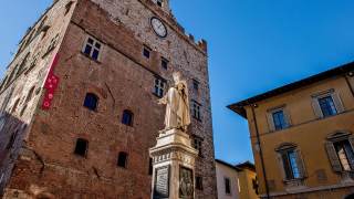 Ripresa dal basso verso l\'alto della statua di Datini in mezzo a piazza del Comune, sullo sfondo il Museo di Palazzo Pretorio